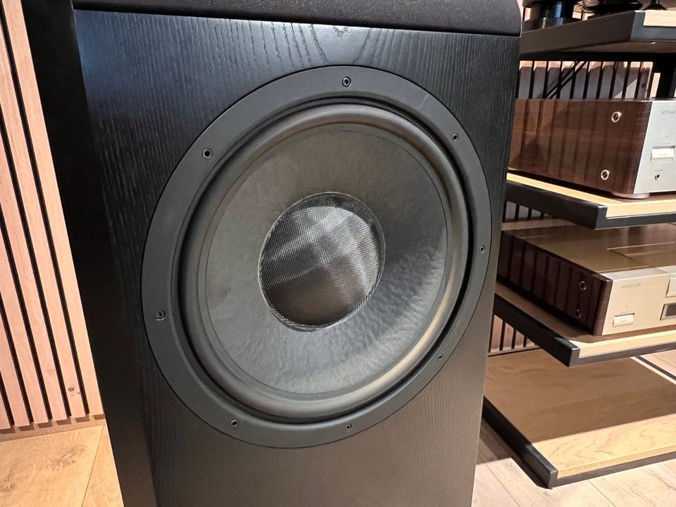 Baswoofer van de B&W Nautilus 801 met zwarte kast naast een hifi-rek