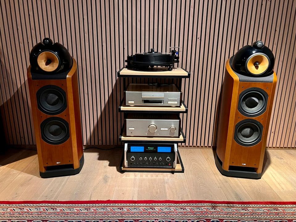 Paar B&W Nautilus 802 luidsprekers in kersenhout naast een hifi-rek met versterkers