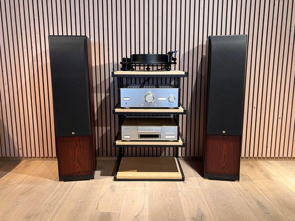 Paar KEF Reference Series Model Three vloerstaanders in donker houtfineer met frontdoek naast hifi-rack
