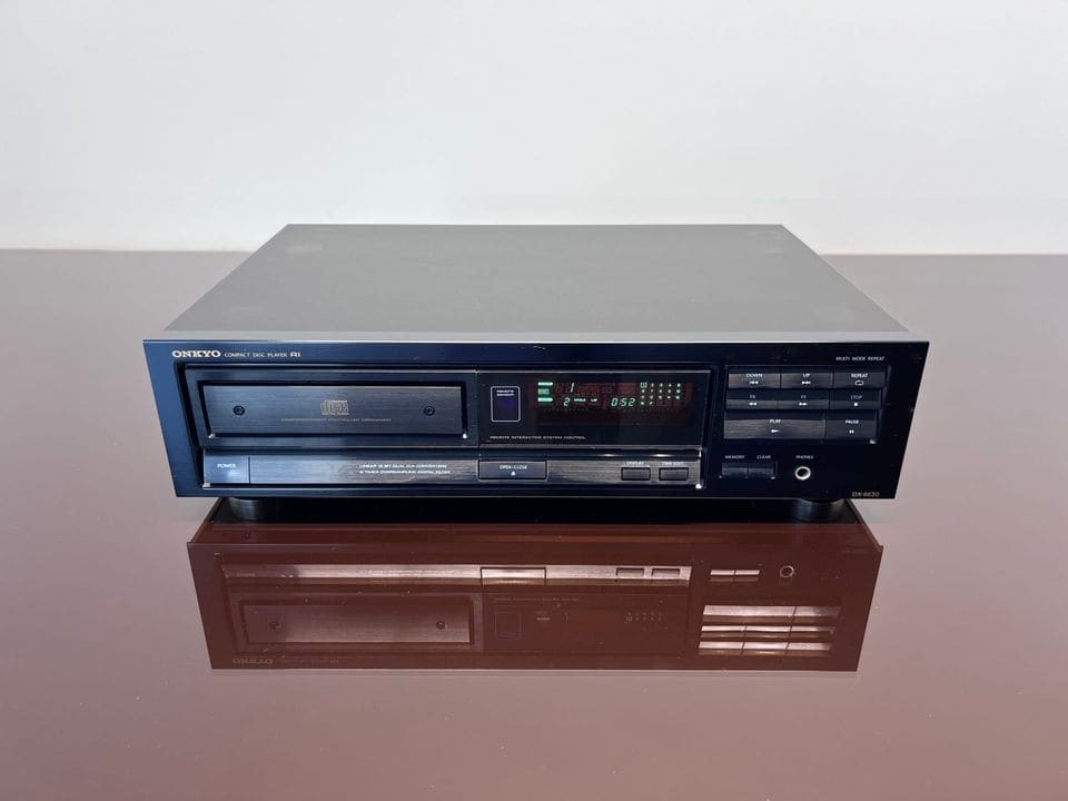 Zwarte Onkyo DX-6630 cd-speler, vooraanzicht op een spiegelende tafel