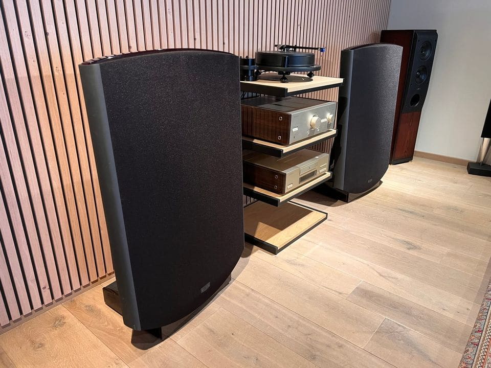 Quad ESL-2812 elektrostatische luidspreker in zwart doek naast een hifi-rack in een luisterruimte