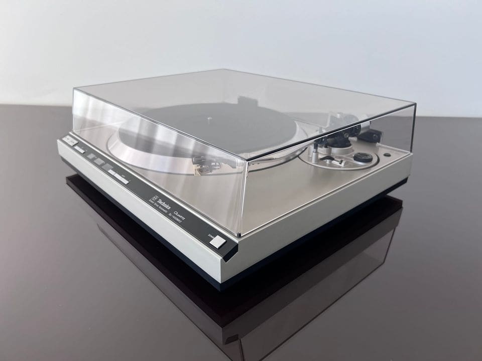 Technics SL-1400 MK2 schuin van links met gesloten stofkap op een spiegelende tafel