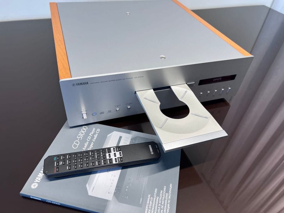 Yamaha CD-S1000 met geopende disclade, afstandsbediening en handleiding