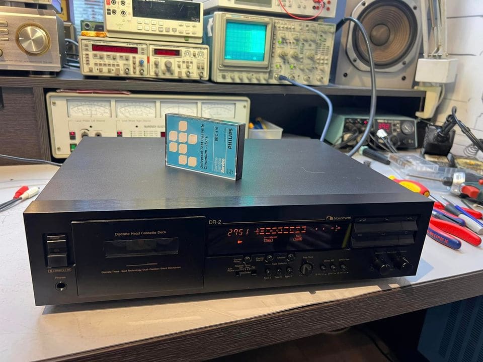 Nakamichi DR-2 cassettedeck in werking op de werkbank, met een Philips-testcassette erop en meetapparatuur erachter