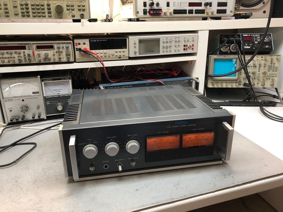 Revox A740 stereo-eindversterker met oranje verlichte piekmeters op de werkbank tussen meetapparatuur